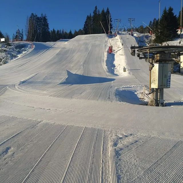 Kveldskjøring i opplyst alpinbakke med skiløpere i heisen og i løypa.
