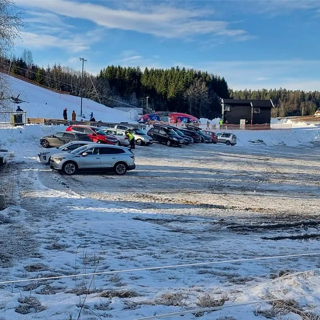 Parkering ved alpinanlegg med biler og snø på bakken.