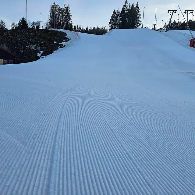 Bred, preparert bakke med hopp og skitrekk langs siden.